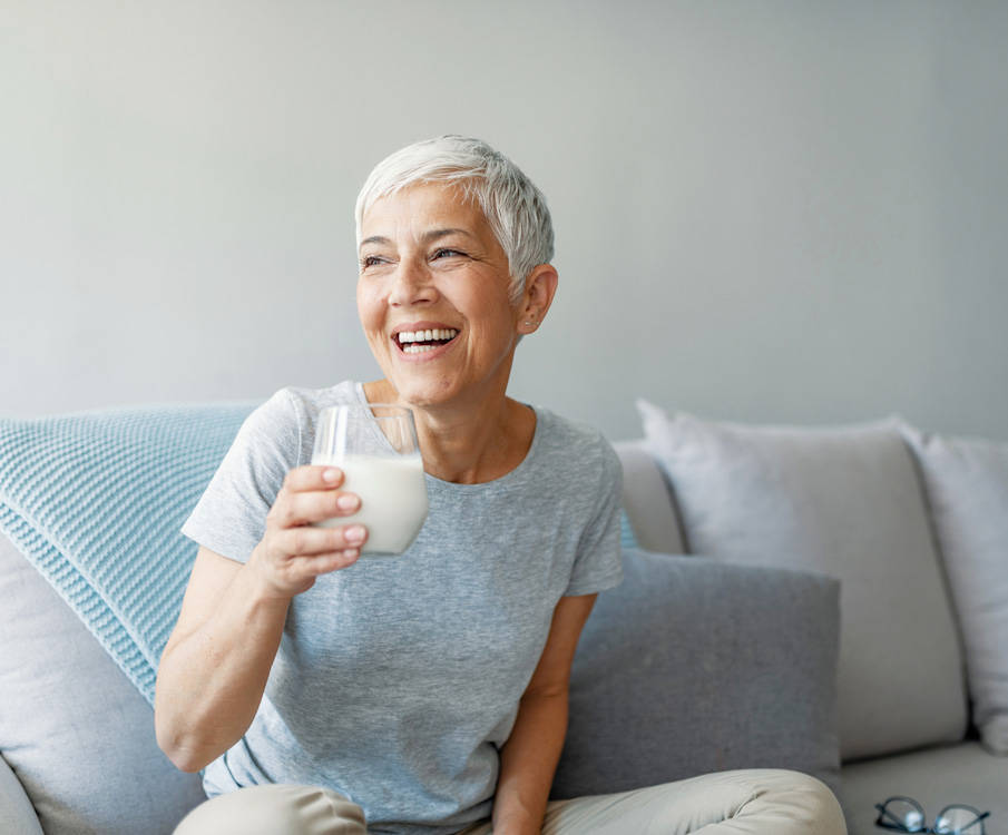 Lächelnde Frau auf dem Sofa mit einem Glas Milch